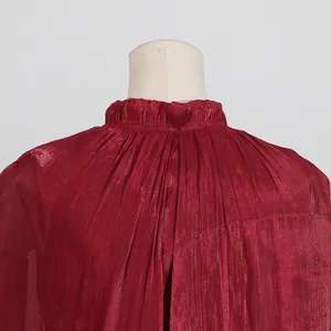 Primer plano de vestido plisado burdeos con elegante detalle de cuello con volantes.