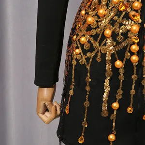 Close-up detail of luxury gold sequin tassels and orange pearls on black vintage dress.