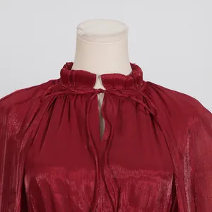 Detalle del vestido rojo vino con cuello de volantes y textura de tela plisada brillante
