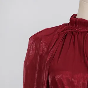 Detalle de un vestido burdeos brillante con cuello de volantes y tela plisada