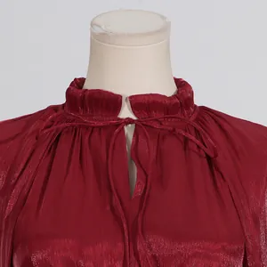 Primer plano del escote con volantes y lazo en un vestido de noche plisado de lujo rojo vino