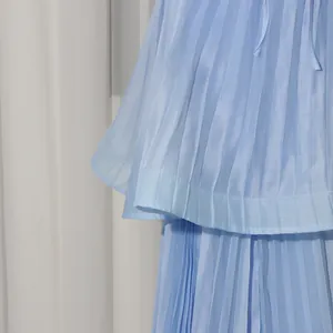 Macro detail shot of a light blue pleated tiered dress showing delicate fabric texture