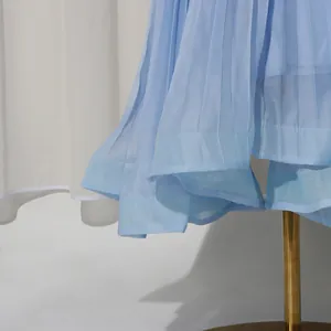 Detail of blue pleated mesh dress showing layered hemline and fine fabric texture.