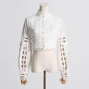 Elegante blusa corta de encaje blanco con botones de perlas y mangas abullonadas.