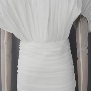 Dettaglio di un abito a pieghe bianco con eleganti arricciature e maniche in velo.