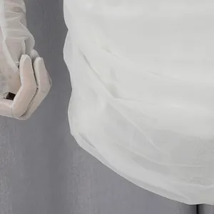Dettaglio del tessuto a rete bianco con elegante design a pieghe 3D su un abito