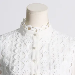 Primer plano de una blusa de encaje blanco estilo retro con cuello alto y botones de perlas