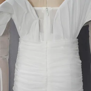 Dettaglio ravvicinato della cerniera invisibile sul retro di un elegante abito bianco plissettato
