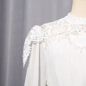 Close-up of elegant white dress featuring intricate lace neckline and pleated sleeves