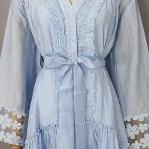 Detalle de vestido retro azul claro con bordado de encaje y puños florales.