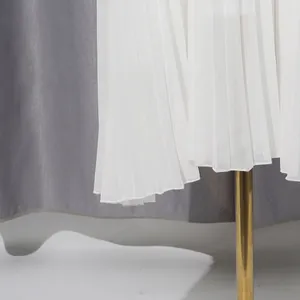 Close-up detail showing the fine pleats and hem of an elegant white chiffon dress