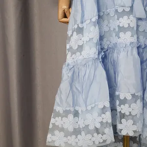 Primer plano del encaje floral blanco y los volantes de un vestido de verano azul claro.