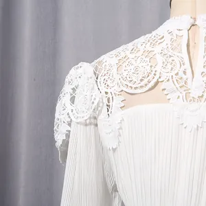 Close-up of delicate lace collar and pleated chiffon sleeves on white dress.
