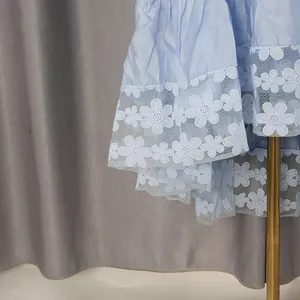 Detalle de bordado de encaje floral en el dobladillo de un vestido francés azul claro