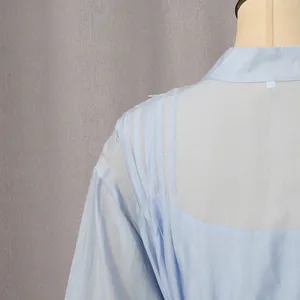 Detalle del hombro plisado y tejido transparente en un elegante vestido vintage azul claro.