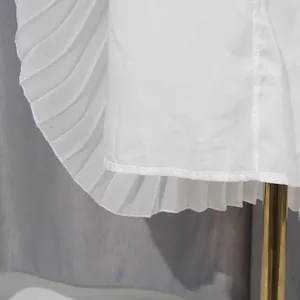 Macro view showing the fine pleated texture and hemline of an elegant white chiffon dress