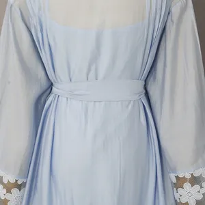 Primer plano de vestido azul claro con puños de encaje floral y detalles plisados