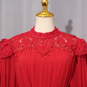 Close-up detail of elegant red dress featuring intricate lace stand collar and pleated chiffon