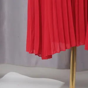 Close-up macro view of the elegant red pleated chiffon fabric hem on an evening dress.