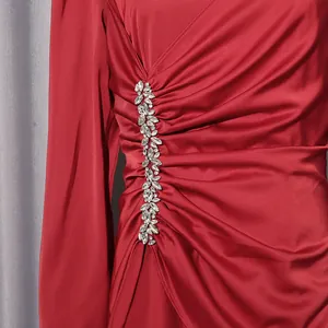 Nahaufnahme eines roten Satinkleides mit Falten und glitzerndem Kristallbesatz.