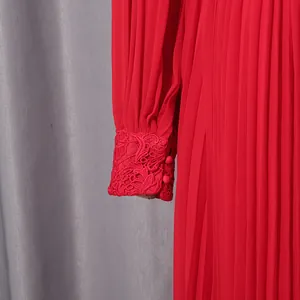 Close-up of red chiffon dress featuring intricate lace cuffs and pleated fabric detail