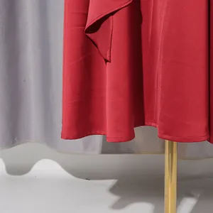 Nahaufnahme des Saums eines eleganten roten Faltenabendkleides und Seidenstoffstruktur