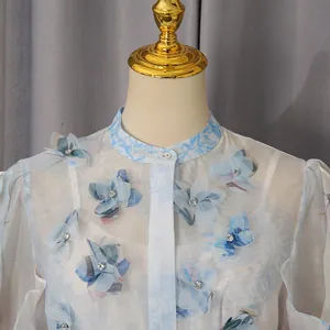 Detailansicht von 3D-Blumenapplikationen mit Strass auf einem blauen Vintage-Kleid