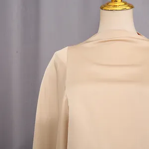 Primo piano dell'elegante tessuto di raso color albicocca con trama simile alla seta.
