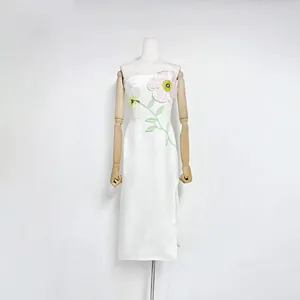 Detailed view of white strapless midi dress with 3D floral embroidery and side slit