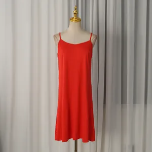 Robe nuisette midi rouge minimaliste présentée sur un mannequin blanc devant un rideau.