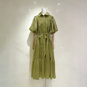 Dettaglio di un abito lungo verde oliva stile corte con maniche a sbuffo ricamate.