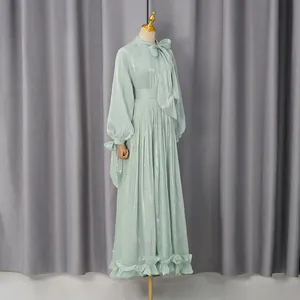 Vista detallada de vestido largo verde menta brillante con tejido plisado y lazo al cuello.