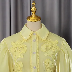Dettaglio dell'abito giallo stile palazzo vintage con ricami e bottoni di strass