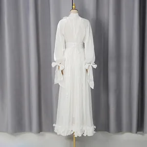Vista trasera de un vestido largo de gasa blanca con mangas de linterna y volantes.