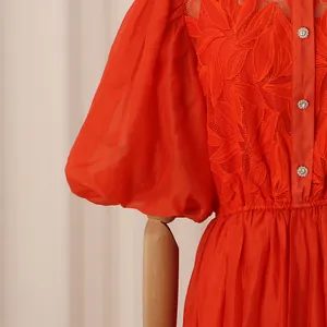 Détail d'une robe orange rétro française avec broderie de feuilles et boutons perle