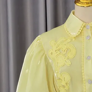 Dettaglio ravvicinato del ricamo in pizzo giallo e dei bottoni di cristallo su abito vintage