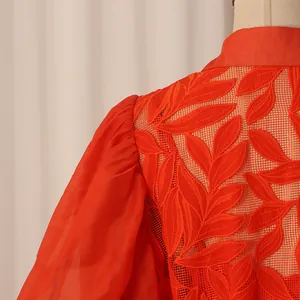 Gros plan du motif de feuilles brodées orange sur résille d'une robe chemise vintage