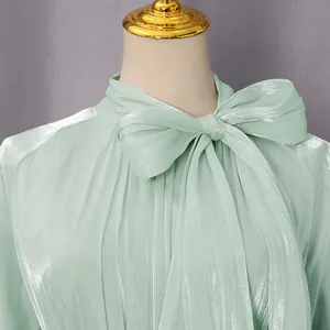 Primer plano de elegante vestido brillante verde menta con textura plisada y lazo