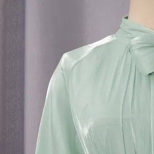 Primer plano de un vestido de gasa verde menta brillante con elegante detalle de lazo