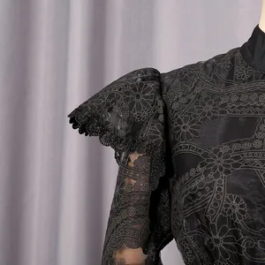 Detailed macro view showing the elegant floral embroidery and lace flounce on the black dress