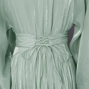 Primer plano de vestido de gasa verde brillante con detalle de cintura corsé con cordones.