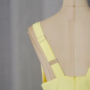 Detail view of yellow dress back strap with adjustable metal buckles and zipper.