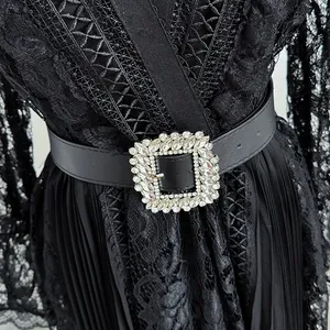 Close-up of black hollow lace dress detail with sparkling rhinestone belt buckle.