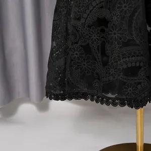 Close-up detail of vintage black dress with floral embroidery and delicate lace trim hem