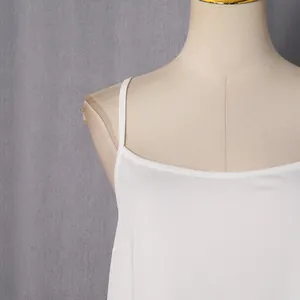 Detail view of the elegant white satin slip dress neckline with delicate spaghetti straps