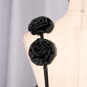 Detailansicht von zwei eleganten schwarzen Stoffrosetten an einem Kleiderschultergurt