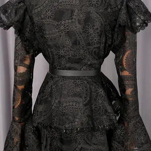 Close-up of elegant black embroidered lace dress with ruffles and flared sleeves detail