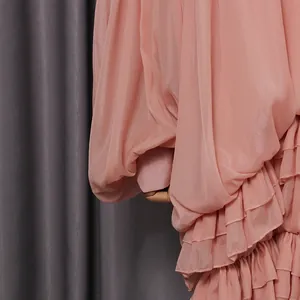Primo piano dei delicati dettagli a balze rosa su un dolce abito in chiffon a pieghe elegante