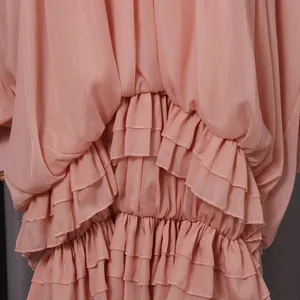 Primo piano di balze a strati e pieghe su un abito estivo rosa antico in stile babydoll.