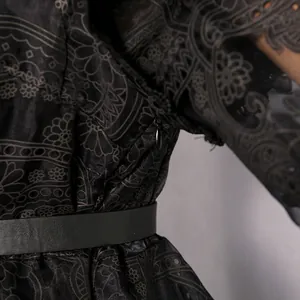 Detailed view showing intricate black embroidery and an invisible side zipper on the dress.